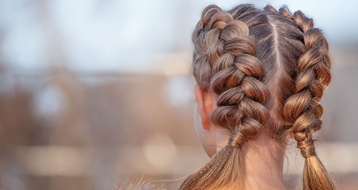 mulher branca de cabelo médio loiro escuro com penteados de duas tranças embutidas